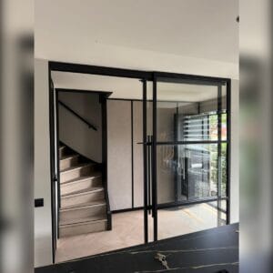 stalen glazen wand met enkele deur en zicht op de trap